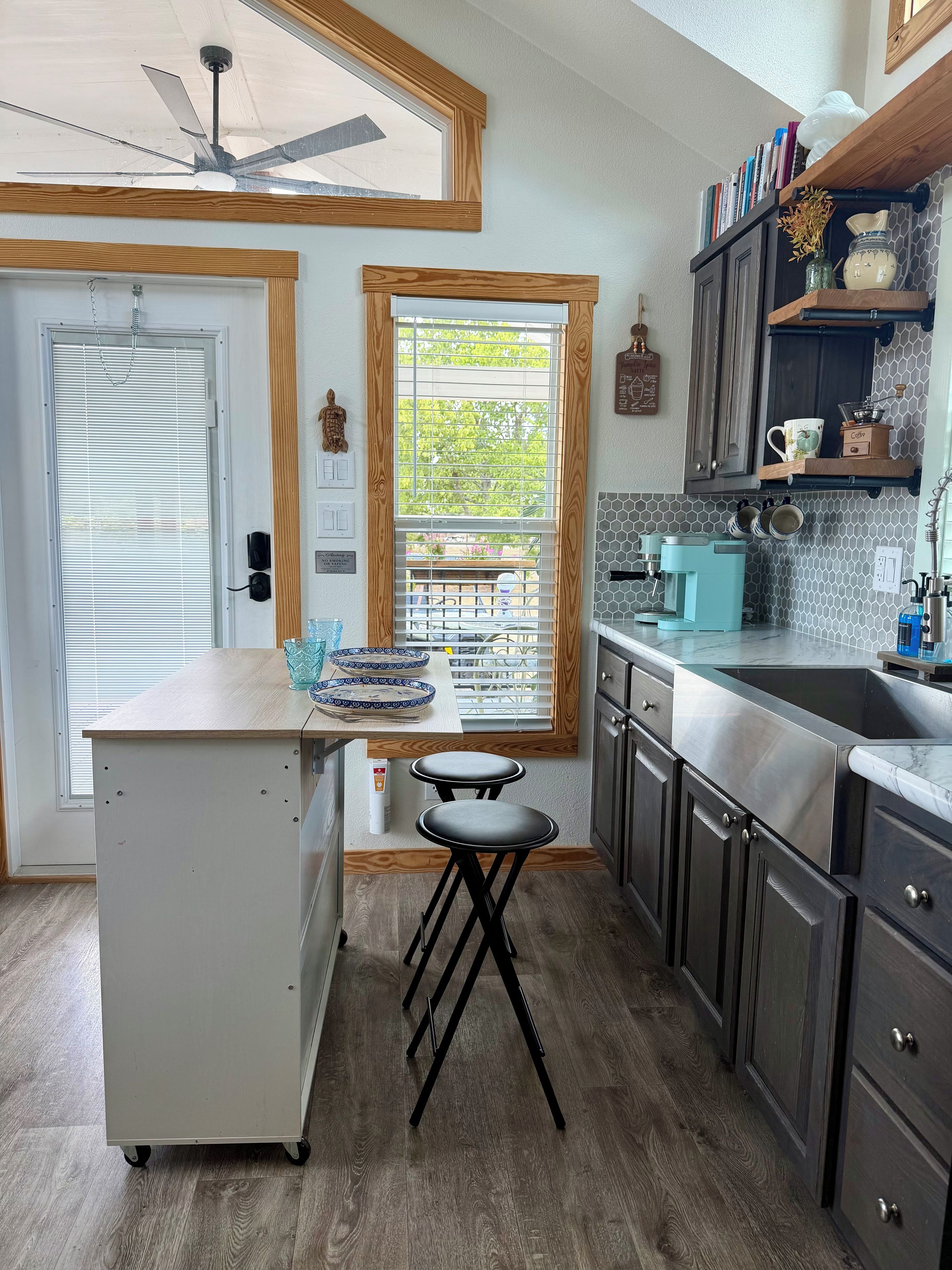 A kitchen with a built-in refrigerator, a coffee machine, and a window with blinds.