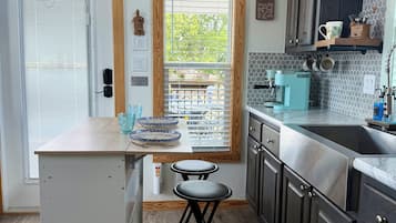 A kitchen with a built-in refrigerator, a coffee machine, and a window with blinds.