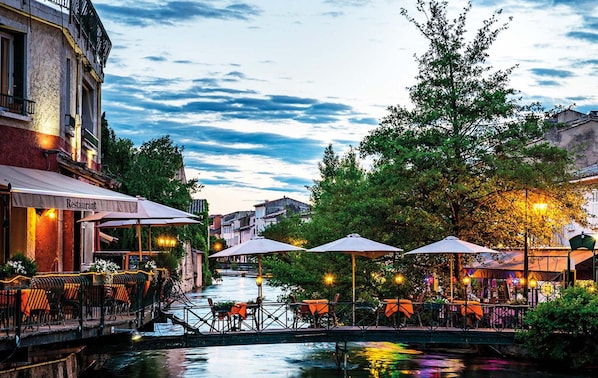 A riverside restaurant with outdoor seating and a bridge. - Provencal Family Getaway for Six (L'Isle-sur-la-Sorgue)