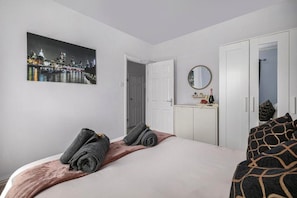 Ein Hotelzimmer mit einem Bett, einem Kleiderschrank, einem Spiegel und einem Stadtbild an der Wand.