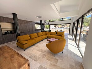 A modern living room with a sectional sofa, a round armchair, and a wooden coffee table. - Villa Mimosa with Private Pool (Saint-Cyr-sur-Mer)