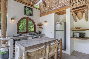 Eine Küche mit einer zentralen Kochinsel, Holzbalken, einem Herd, einem Kühlschrank und einer Mikrowelle.