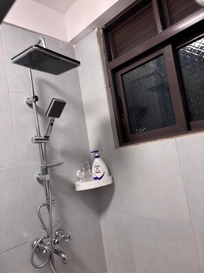 Ein Badezimmer mit Dusche, Fenster und einer Seifenspender an der Wand.