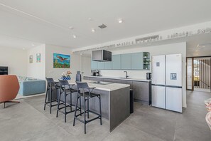 Eine moderne Küche mit einer zentralen Kochinsel, Barhocker und einem eingebauten Kühlschrank.