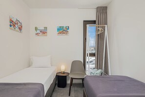 Ein Hotelzimmer mit einem Bett, zwei Nachttischen, einem Sessel, einem Kleiderschrank und einem Fenster mit Vorhängen.