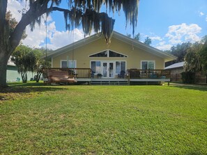A two-story house with a covered porch, a swing set, and a well-maintained lawn. - Serene Lakefront Retreat on Lake Santa Fe – Panoramic Water Views & Private Dock (Waldo)