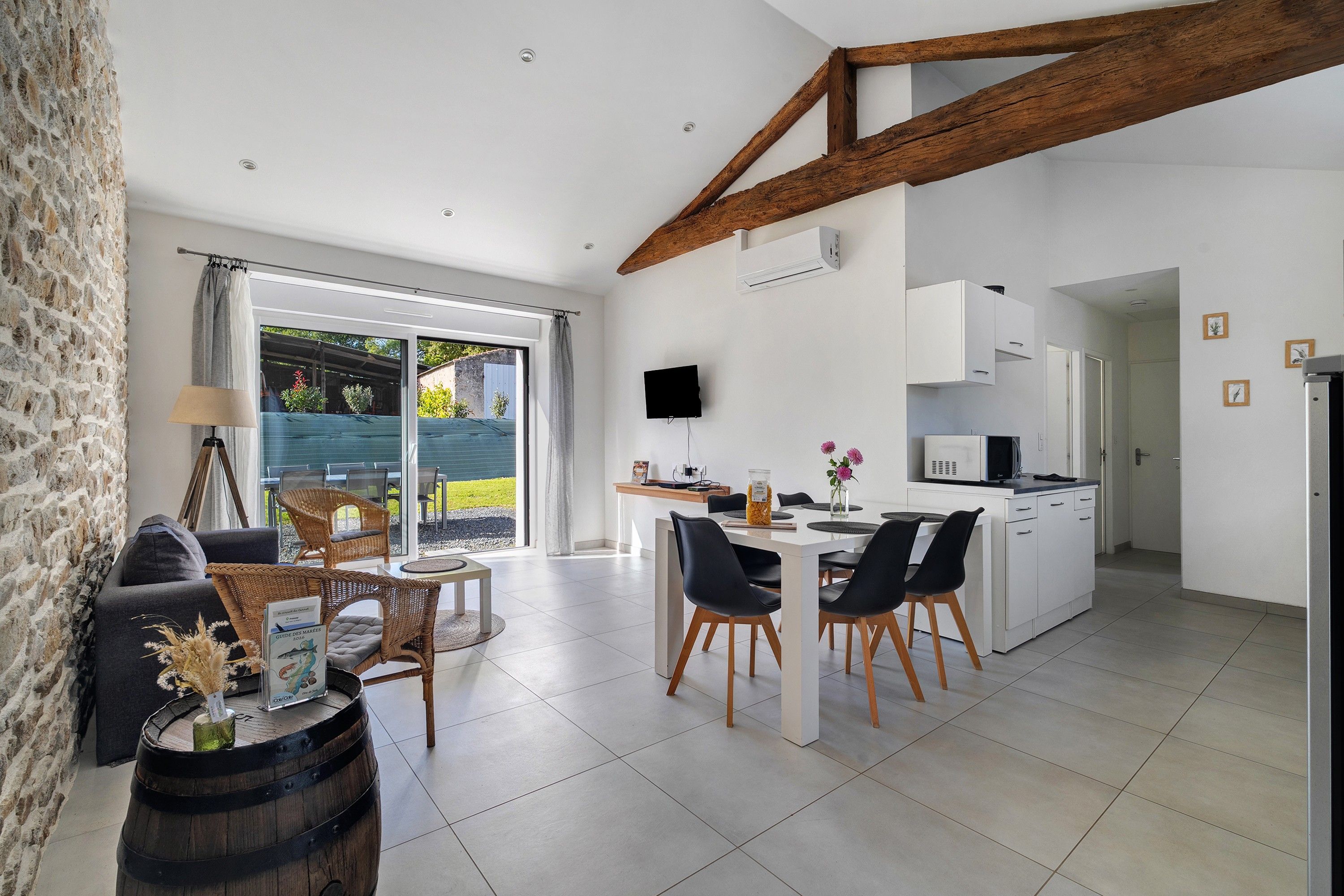 A modern kitchen with white cabinets, a dining area with a table and chairs, and a stone wall on one side.
