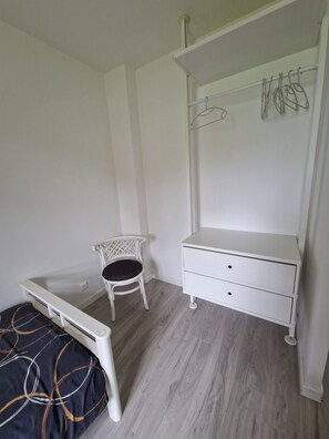 Een slaapkamer met een bed, een stoel, een dressoir en een kledingkast.