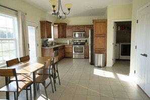 A kitchen with wooden cabinets, a stainless steel refrigerator, a microwave, and a stove. There is a dining table with chairs. - Peaceful Country Escape in Eagleville TN (Eagleville)