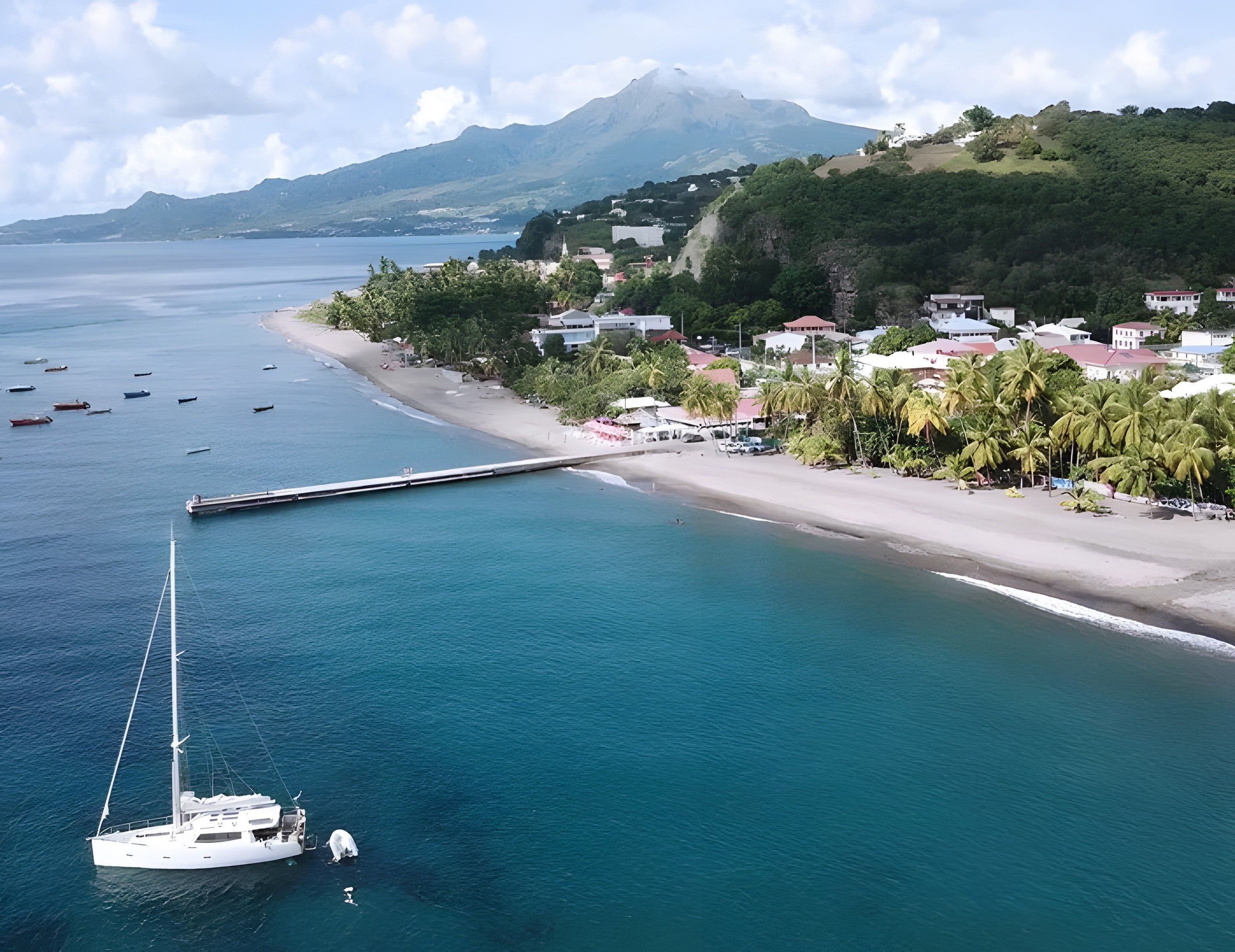 A coastal town with a marina, a beach, and a mountain in the background.