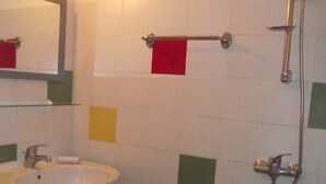 Ein Badezimmer mit Waschbecken, Spiegel, Dusche und gefliesten Wänden.