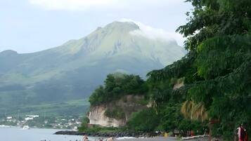 Une plage avec une montagne en arrière-plan, un ciel dégagé et quelques personnes.