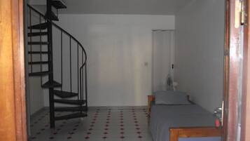 Um quarto com escada em espiral, uma cama e uma pequena mesa.