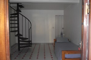 Una habitació amb una escala espirall i un llit, a més d'una taula petita.