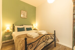Ein Schlafzimmer mit einem Bett, zwei Nachttischlampen, einem Wandbild und Holzboden.