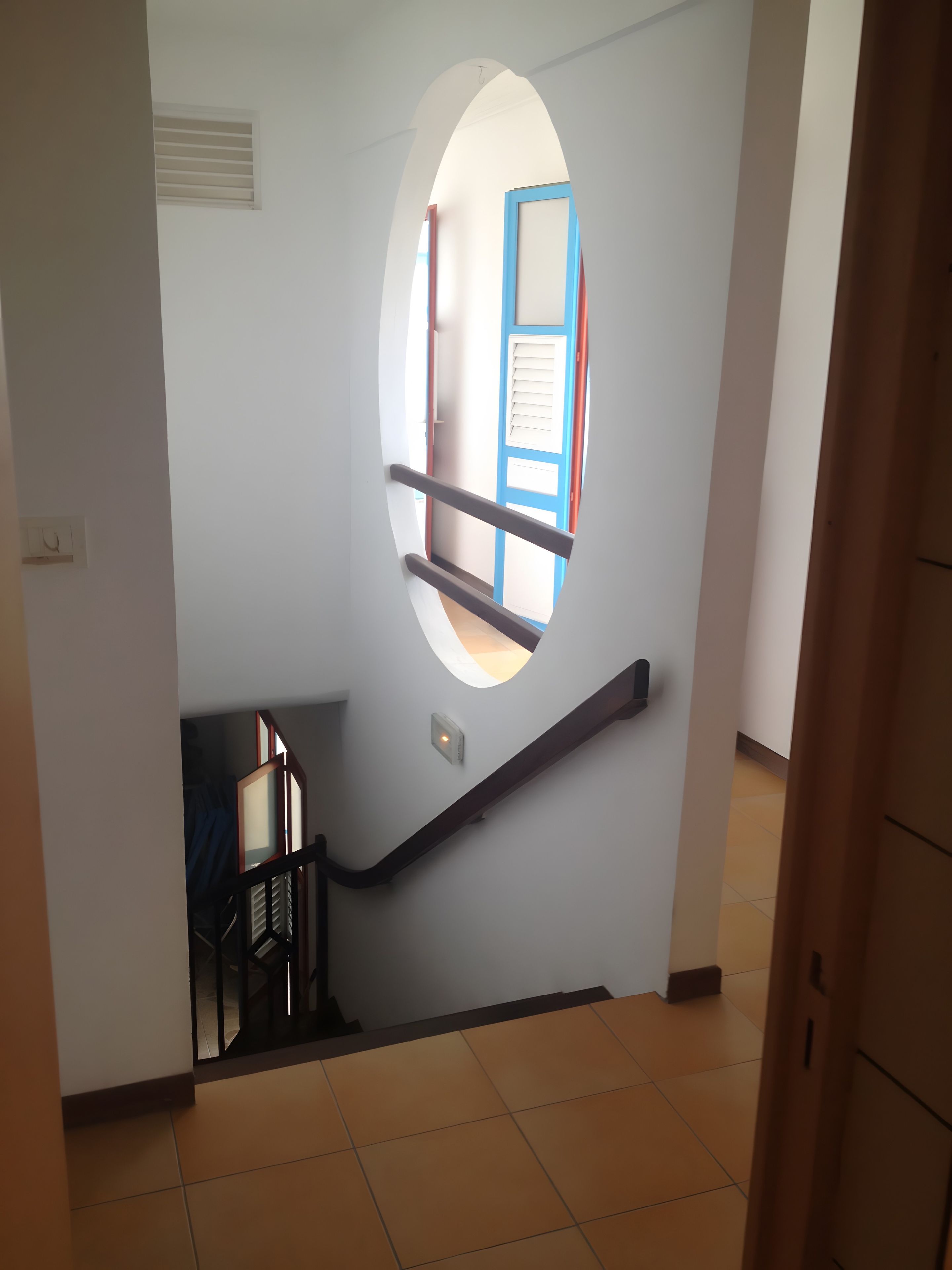 A staircase with a handrail, a window, and a door with a blue frame.