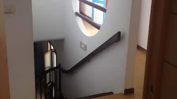 A staircase with a handrail, a window, and a door with a blue frame.