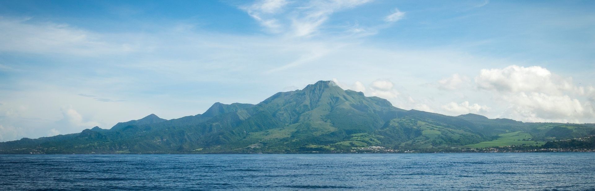 Une chaîne de montagnes sous un ciel dégagé et une mer calme.