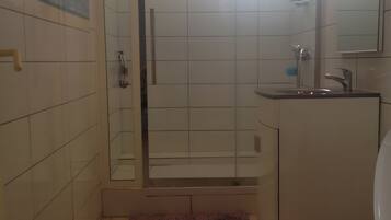 A bathroom with a toilet, a shower, and a sink.