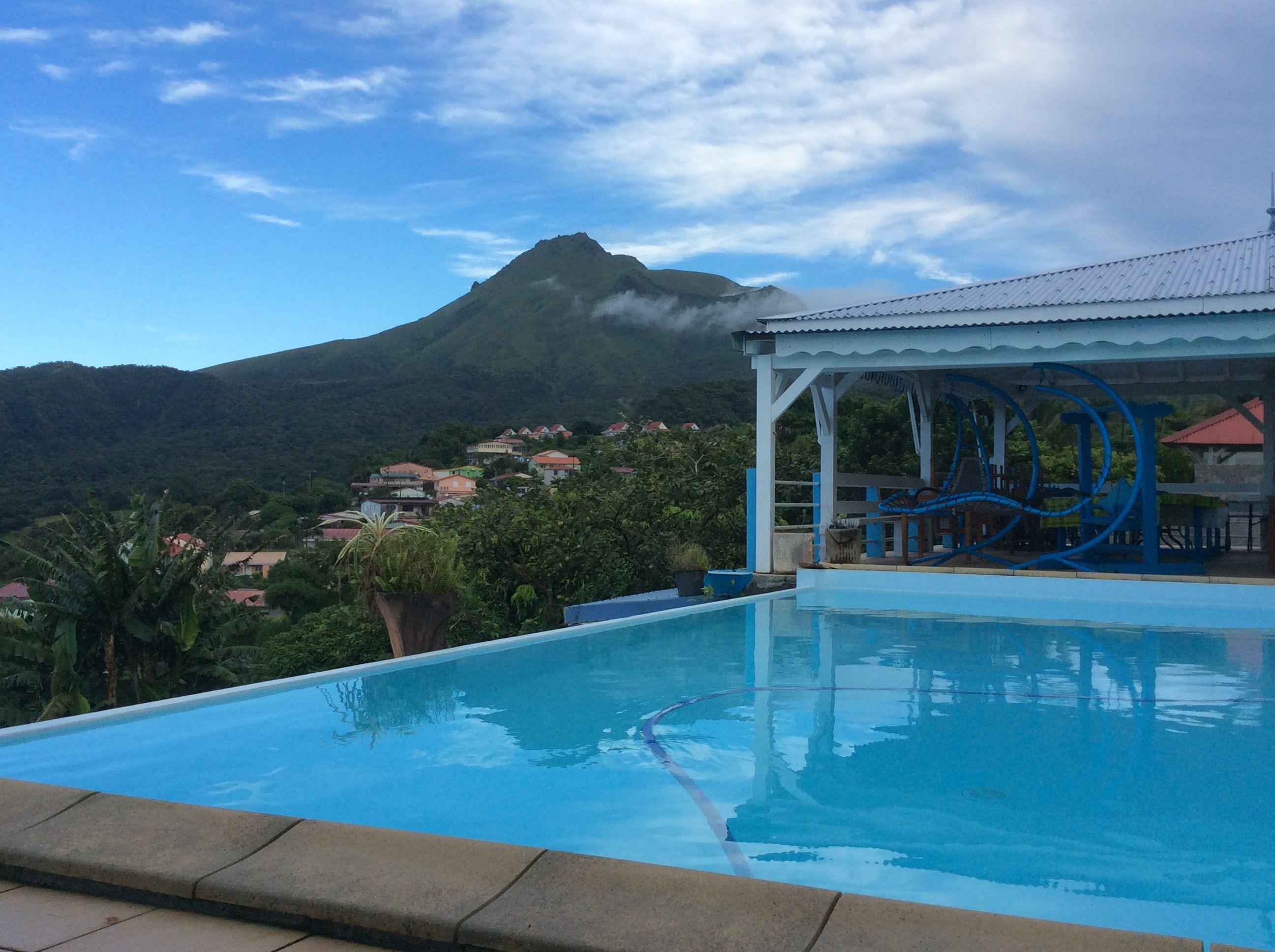 A swimming pool with a view of a mountain and a covered area with a water slide.