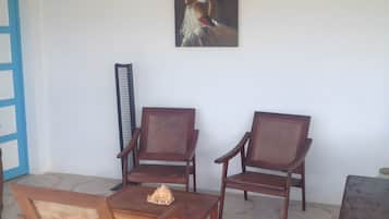 A room with a dining table, two wooden chairs, a bench, and a painting on the wall.