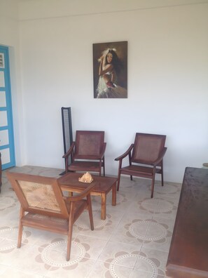 Una habitación con una mesa de comedor, dos sillas de madera, un banco y un cuadro en la pared.
