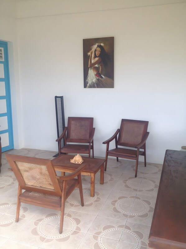A room with a dining table, two wooden chairs, a bench, and a painting on the wall.