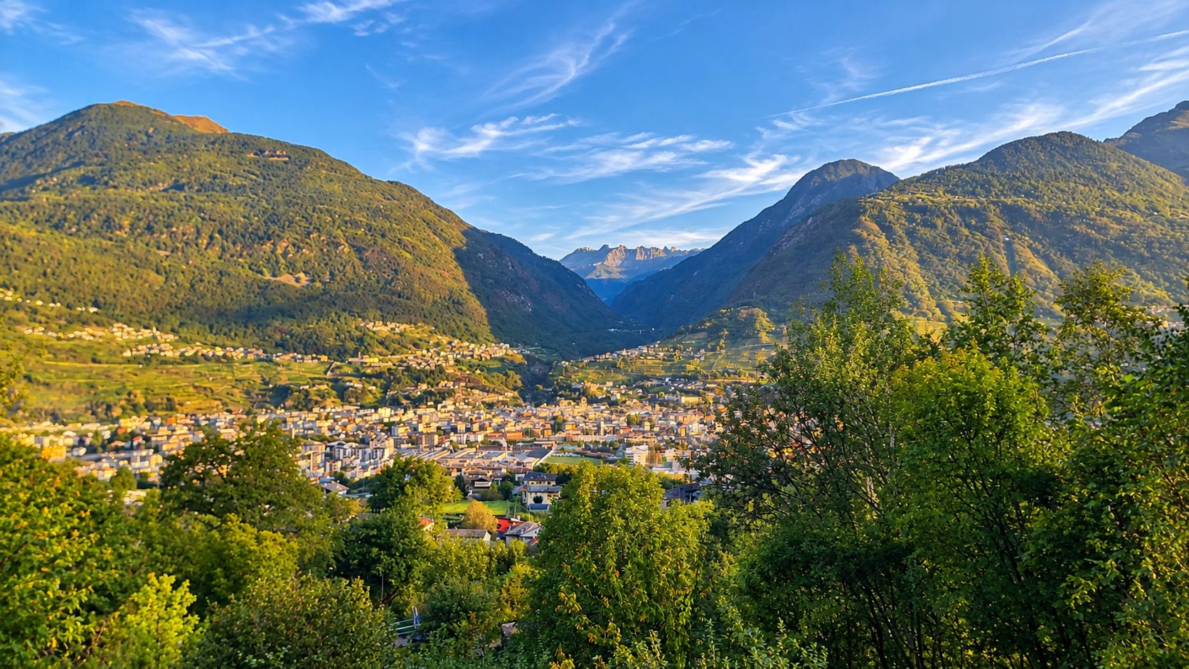 Een stad gelegen in een vallei, met bergen op de achtergrond.