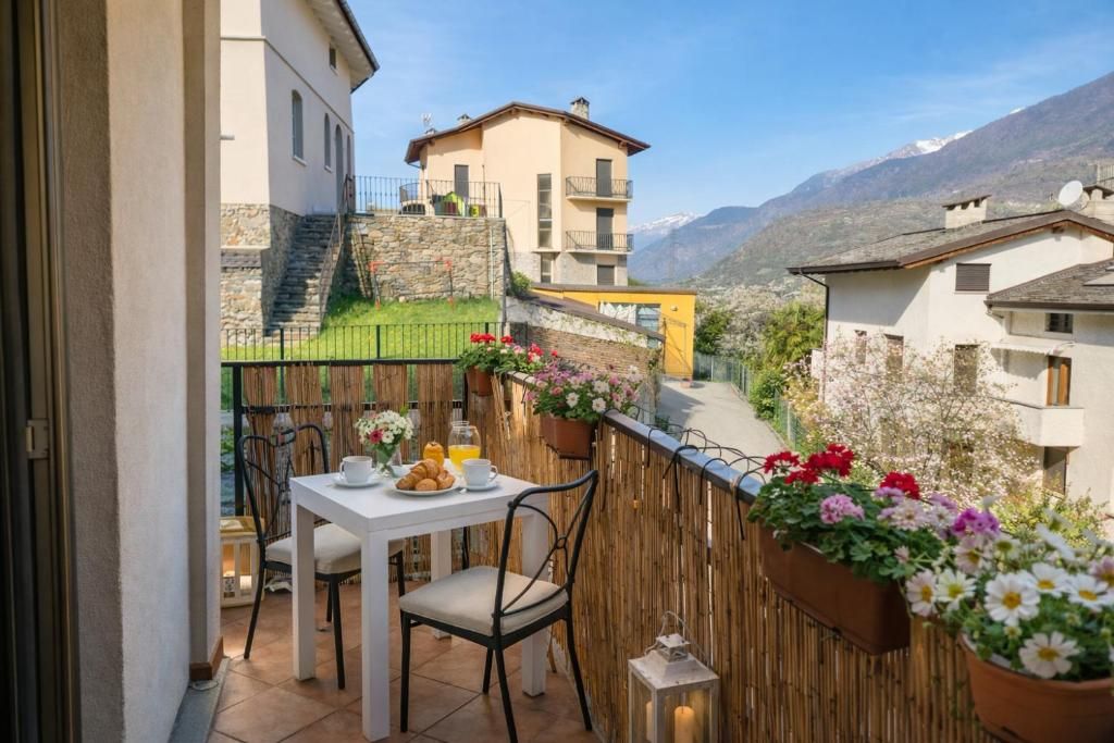 Un balcon avec une table préparée pour le petit-déjeuner, offrant une vue sur un paysage montagneux.
