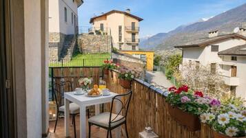Un balcon avec une table préparée pour le petit-déjeuner, offrant une vue sur un paysage montagneux.