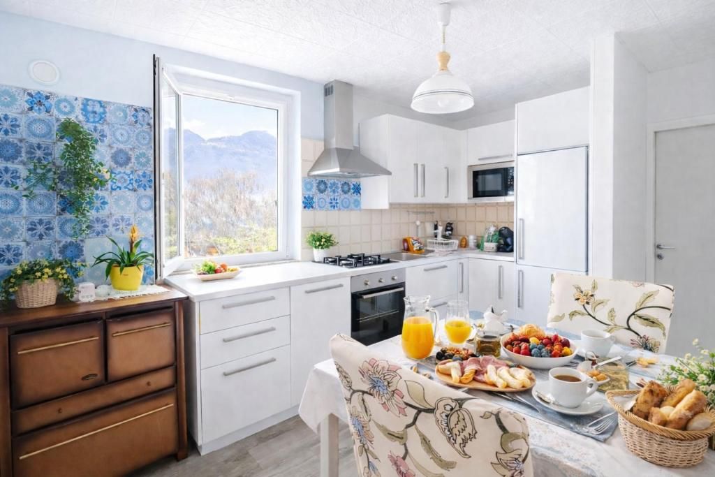Une cuisine moderne avec des meubles blancs, une cuisinière et un coin repas où une table est dressée pour le petit-déjeuner.