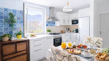 Une cuisine moderne avec des meubles blancs, une cuisinière et un coin repas où une table est dressée pour le petit-déjeuner.