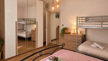 Een compacte slaapkamer met stapelbedden, een garderobe, een nachtkastje met lamp en een spiegel.