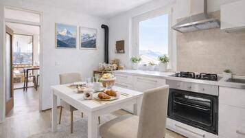 Una cocina moderna con comedor, ventanas amplias y vista a las montañas.