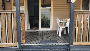 A wooden deck with a covered area, a signpost with destination names, and a table with chairs.