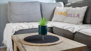 Une petite table en bois, sur laquelle repose une nappe en fibres tressées et une plante verte dans un pot bleu.