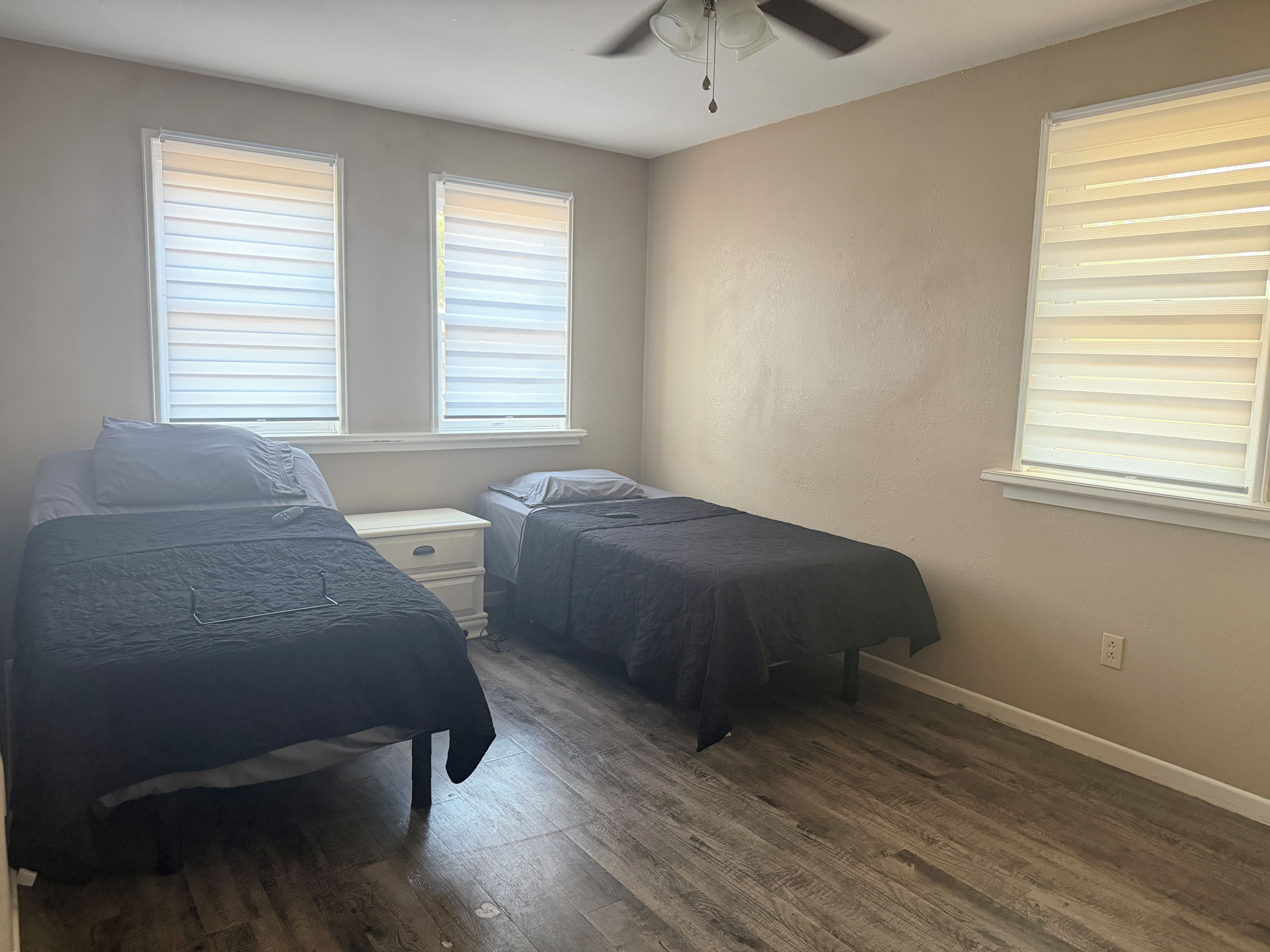 Une chambre avec deux lits, une table de chevet et un ventilateur de plafond.