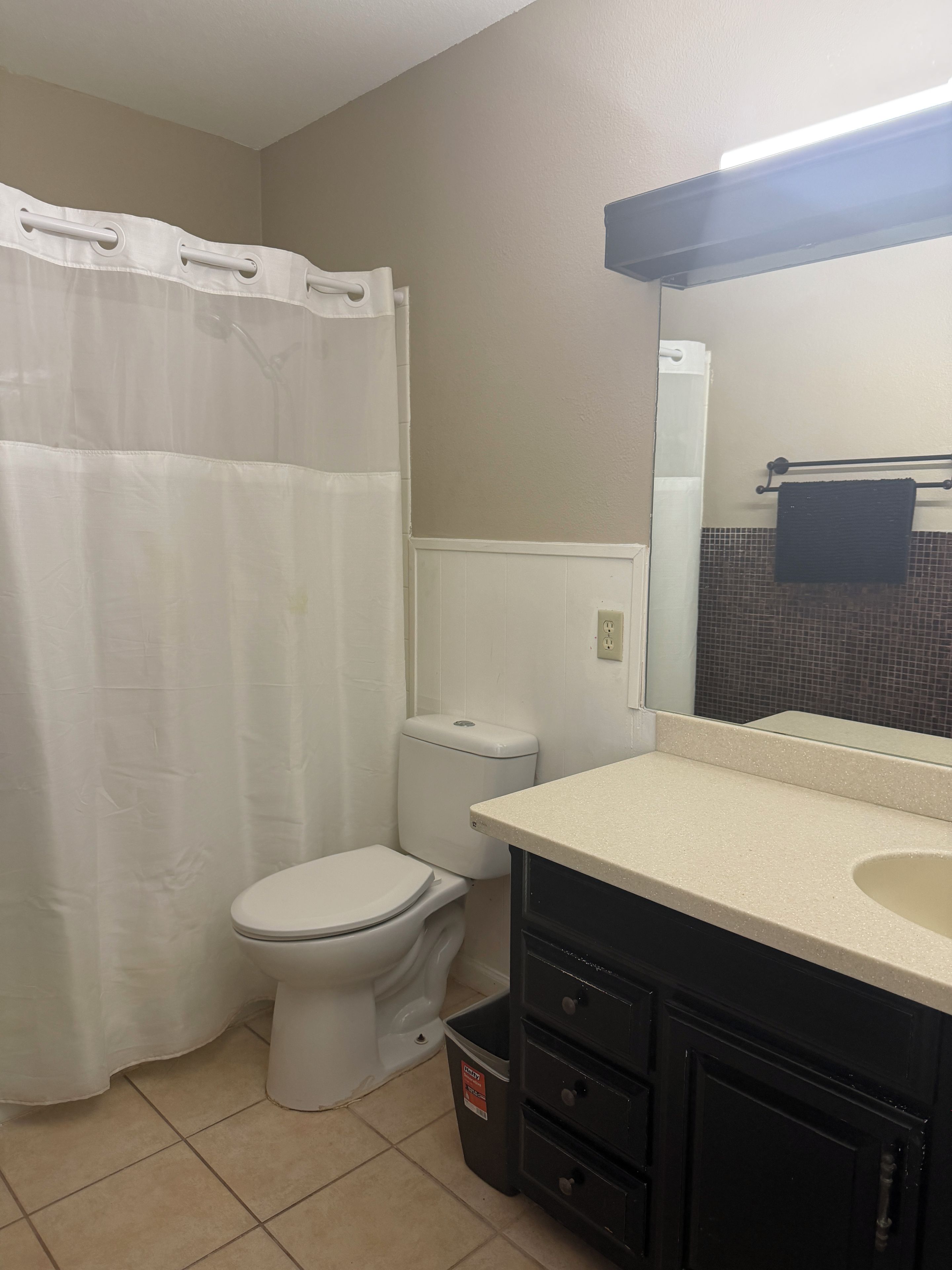 A bathroom with a toilet, a sink, a mirror, and a shower curtain.