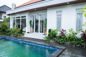 Um imóvel residencial com piscina, varanda coberta e diversas plantas.