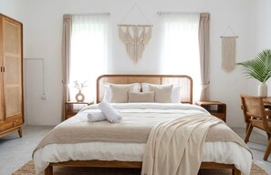 Ein ordentlich eingerichtetes Schlafzimmer mit einem großen Bett, Nachttischen, einem Kleiderschrank und dekorativen Wandbehängen aus Makramee.