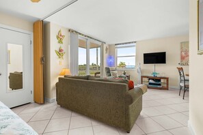 Un salon avec un canapé, un téléviseur et une vue sur l’extérieur.
