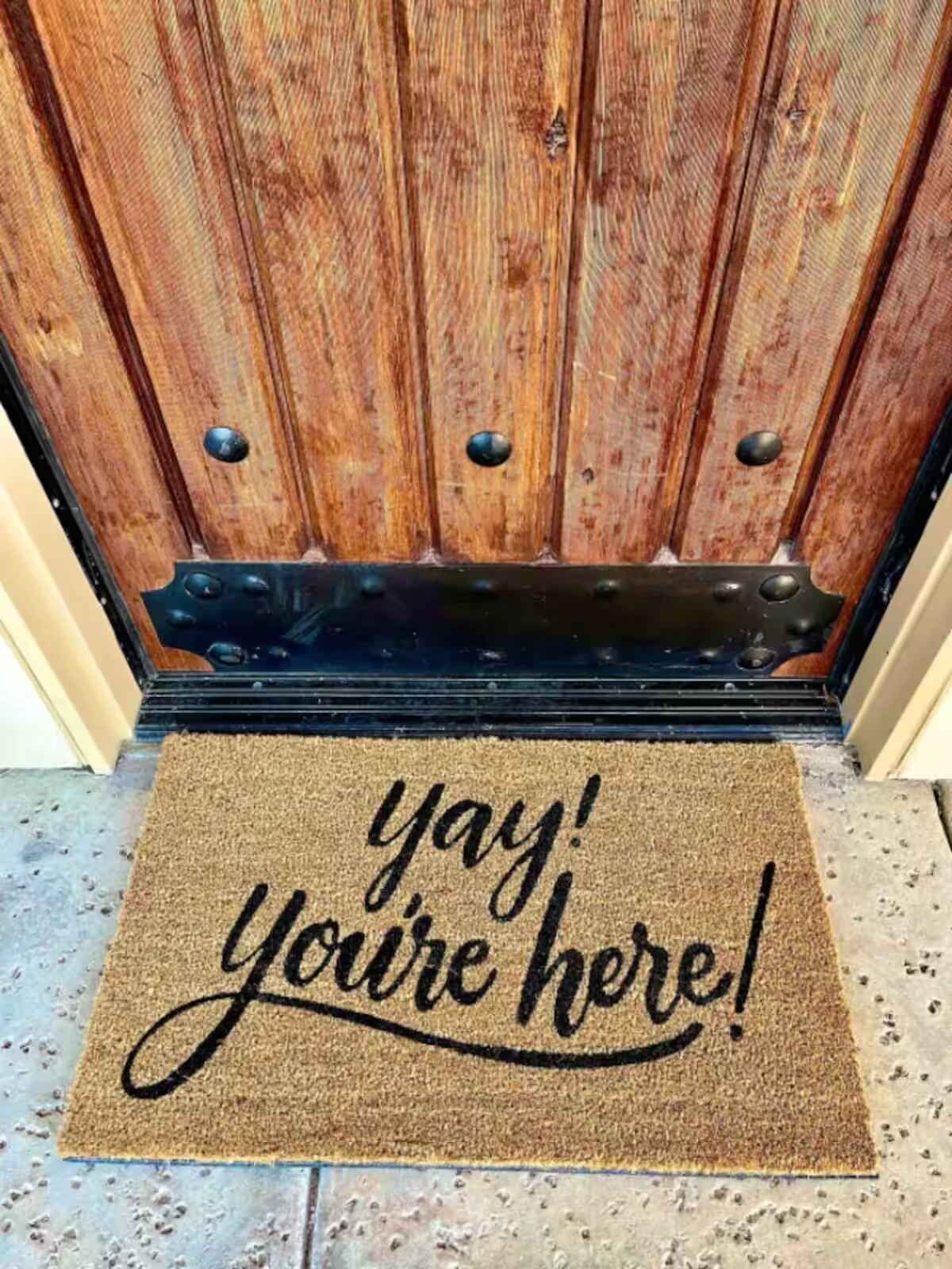 Puerta de madera con felpudo que dice '¡genial, ya llegaste!'