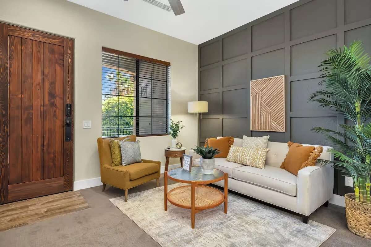 Una sala de estar con sofá, sillón, mesa de centro y una planta en maceta.