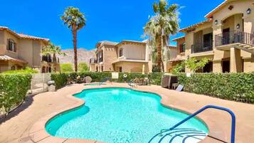 A swimming pool surrounded by palm trees and a clear blue sky.