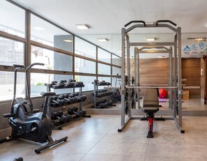 Een sportschool met fitnessapparatuur, gewichtrekken en een spiegelwand.