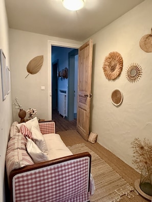 A cozy room with a checkered sofa, a wooden door, and wall decor including a leaf and sunburst patterns. - "The Squirrels of the Park" 400 meters from the beach (Royan)