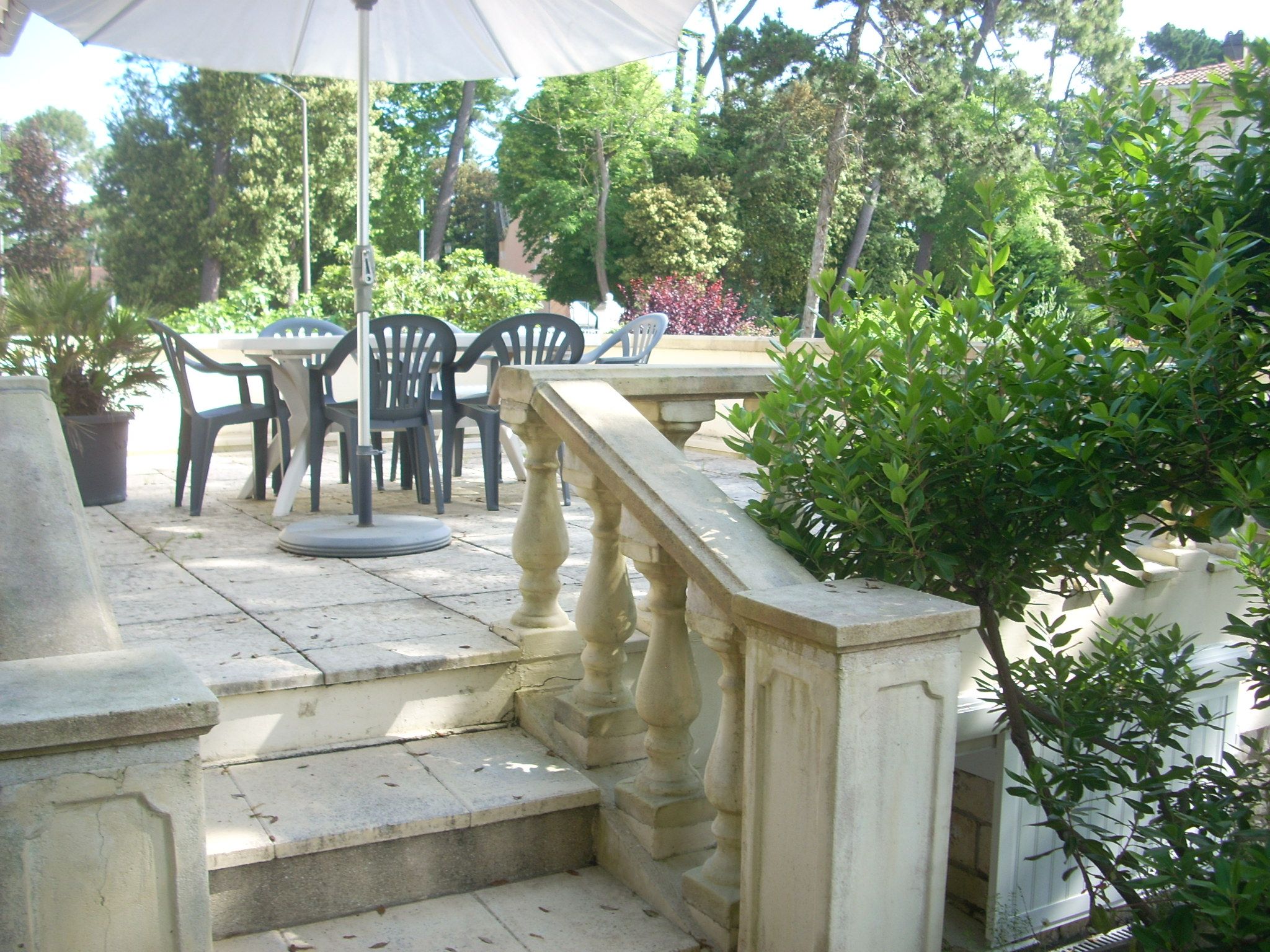 A stone staircase leading to a terrace with outdoor seating and a white umbrella.
