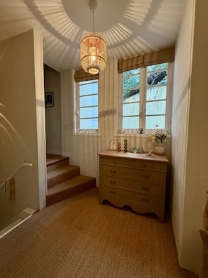 A staircase leading to a landing with a wooden dresser and a hanging light fixture. - "The Squirrels of the Park" 400 meters from the beach (Royan)