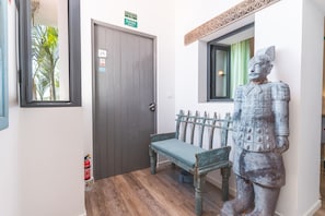 Ein Flur mit einer Bank, einer Tür mit einem Notausgangsschild und einer Statue.