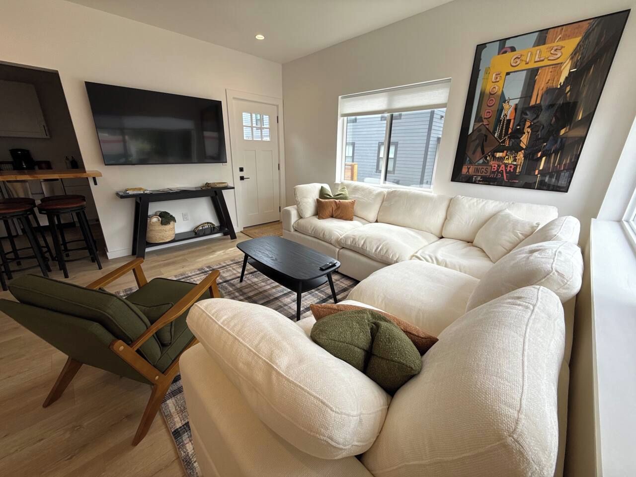 A modern living room with a sectional sofa, a small coffee table, and a TV mounted on the wall.